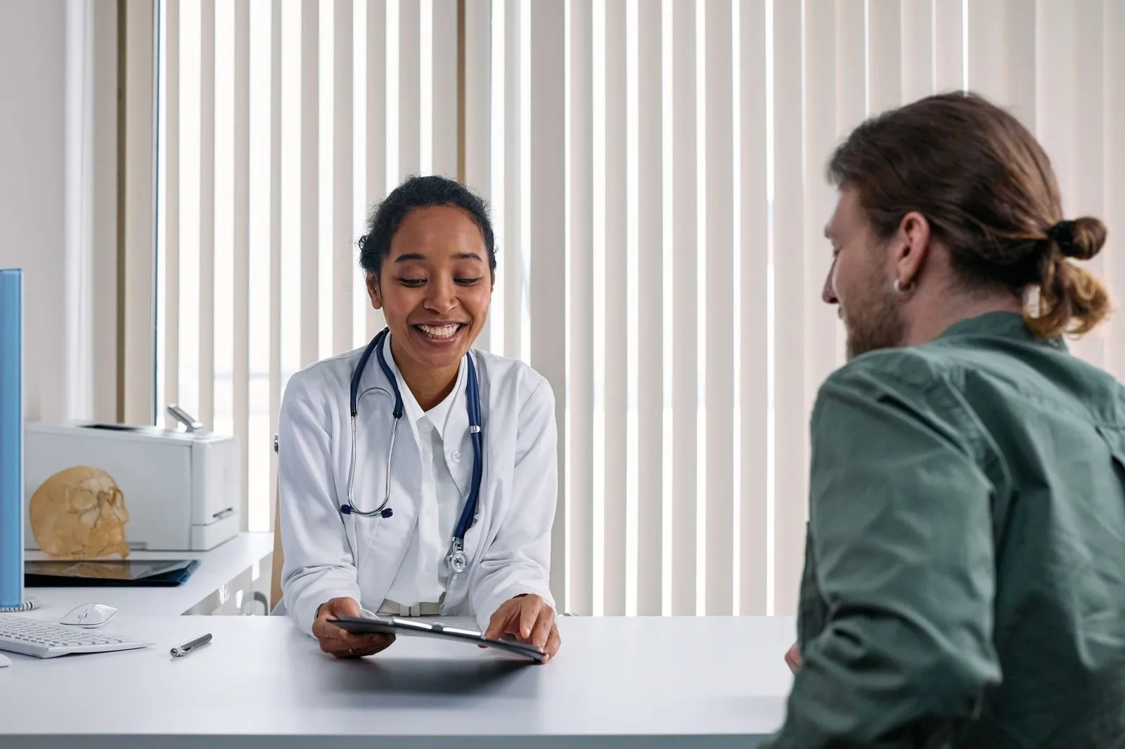 Médica sorridente conversando com paciente em consultório
